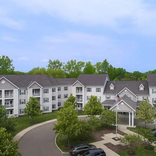 A suburban apartment complex surrounded by lush greenery and a parking lot.