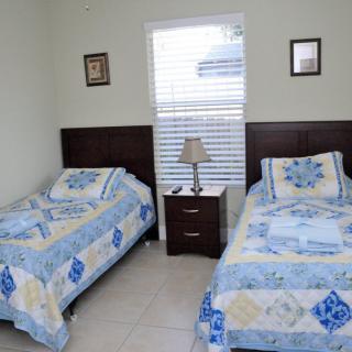 A cozy bedroom with two twin beds, a nightstand with a lamp, and a window providing natural light.