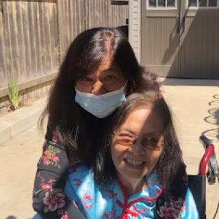 A joyful moment shared between a caregiver and an elderly woman, enjoying the sunshine outdoors.