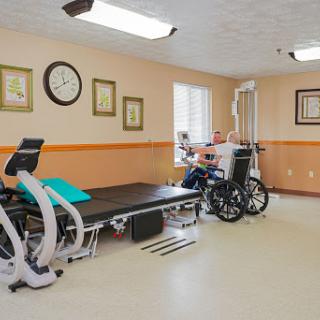 A therapy room equipped with exercise equipment and a wheelchair, designed for rehabilitation.