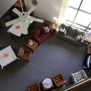 A cozy living room with comfortable seating, tables, and a ceiling fan viewed from above.