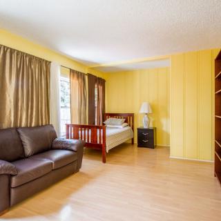 A spacious bedroom with yellow walls, featuring a bed, sofa, and wooden flooring.