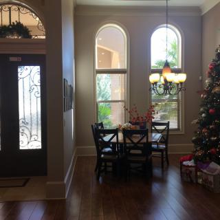 A cozy dining area decorated for the holidays with a Christmas tree and gifts beside a well-lit window.
