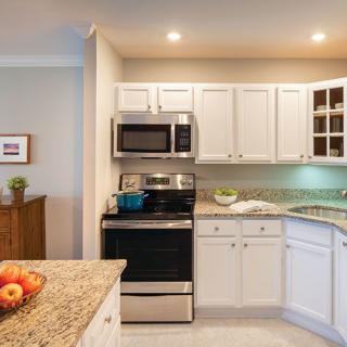 A modern kitchen with white cabinets, granite countertops, and stainless steel appliances.