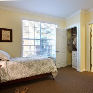 A cozy bedroom with a large window and an open closet.