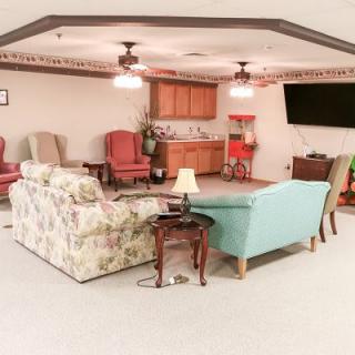 A cozy living room with various seating options, a television, and warm lighting.