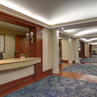 Hotel lobby with a reception desk and carpeted hallway.