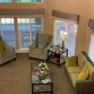A cozy living room with sofas, chairs, and a coffee table by large windows.