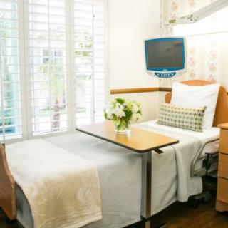 A well-furnished hospital room with a patient bed, bedside table, and a flower arrangement for a comforting atmosphere.