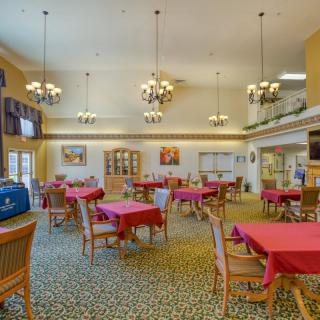 An elegant dining room with multiple tables and chairs, adorned with chandeliers and decorative elements.