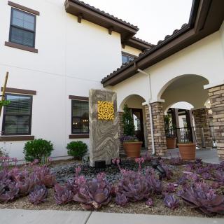A modern house facade with a landscaped garden and arched entryway.