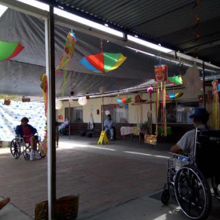 A vibrant indoor community event featuring individuals in wheelchairs, decorated with colorful banners.