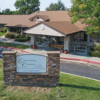 A building entrance with a sign and landscaped surroundings.