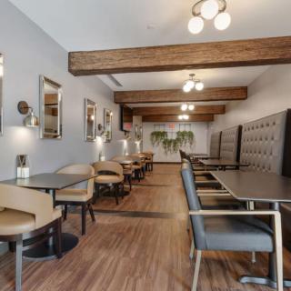 A modern restaurant interior featuring wooden beams, elegant lighting, and comfortable seating.
