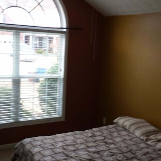 A cozy bedroom with a large window providing natural light.