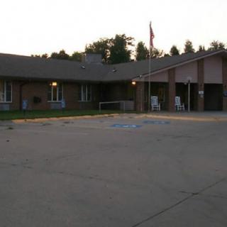 A building with a parking lot at sunset, featuring a flagpole and surrounding trees.