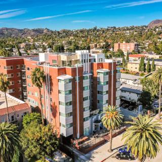 An aerial view of a modern apartment building surrounded by palm trees in an urban setting.