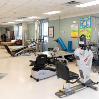 A well-equipped rehabilitation gym featuring various exercise machines and mats for physical therapy.