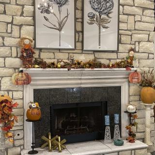 A cozy stone fireplace adorned with fall decorations, including pumpkins and candles, creating a warm autumn atmosphere.