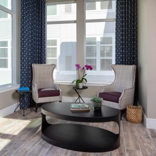 A cozy living room corner featuring two patterned chairs and a round coffee table with an orchid centerpiece.