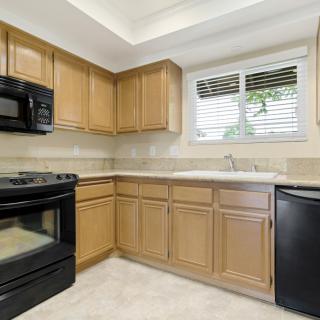 A modern kitchen with wooden cabinets and black appliances.