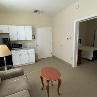 A small apartment living space with a kitchenette, sofa, and an adjoining bedroom.