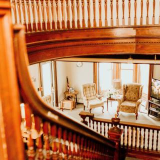 A beautifully crafted wooden staircase overlooking a cozy living room with antique furniture.