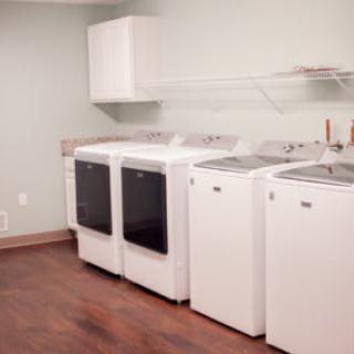 A clean and organized laundry room with multiple washing machines and dryers.