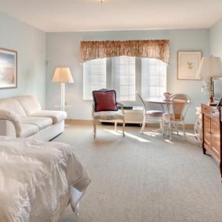 A cozy and well-lit bedroom featuring a sofa, bed, and a small seating area by the window.