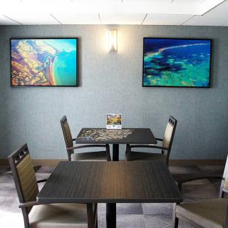 A cozy dining area with two tables, chairs, and vibrant wall art.