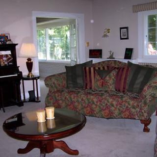 A cozy living room with a floral sofa, wooden coffee table, and a piano in the corner.