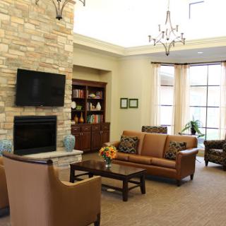 A cozy living room featuring a stone fireplace, comfortable seating, and ample natural light.