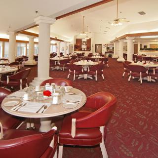 A spacious and elegantly decorated restaurant dining area with red chairs and neatly set tables.