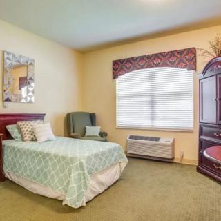 A cozy bedroom with a single bed and armchair near the window.