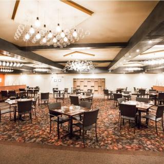 An elegant, empty restaurant dining room with neatly arranged tables and chandeliers.