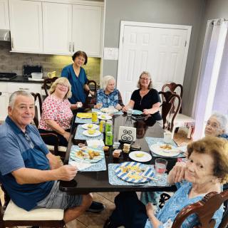 A group of people enjoying a meal together in a kitchen setting.