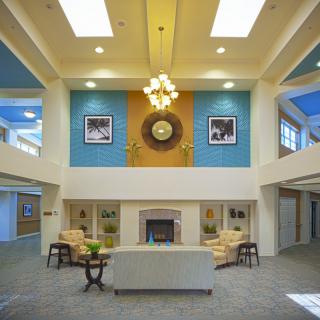 A modern lobby with a central fireplace, elegant chandelier, and comfortable seating area.