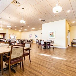 An empty dining area with neatly arranged tables and chairs, featuring warm lighting and a wooden floor.