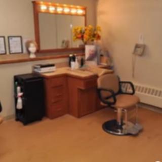 A cozy hair salon setup with a styling chair, vanity mirror, and workspace.