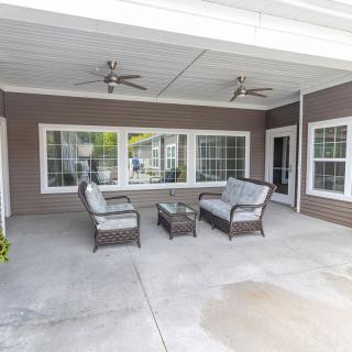 A covered patio with comfortable outdoor seating and ceiling fans.