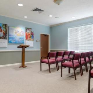 An empty meeting room with rows of chairs and a podium.