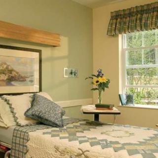 A cozy bedroom or hospital room with a bed, window, and decorative touches.