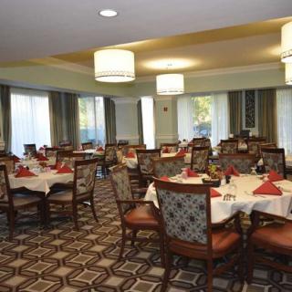 An elegant dining room with set tables and chairs, featuring stylish lighting and decor.
