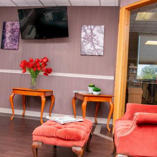 A cozy lobby area with stylish furniture and decor, featuring a TV and vibrant flowers.