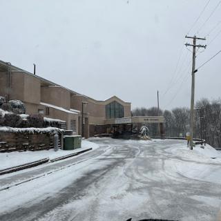 A snowy scene capturing a quiet road lined with buildings, showcasing the serene yet chilly atmosphere of winter.
