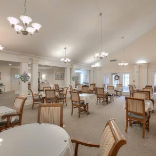 A spacious and elegantly lit dining room with several tables and chairs arranged neatly.