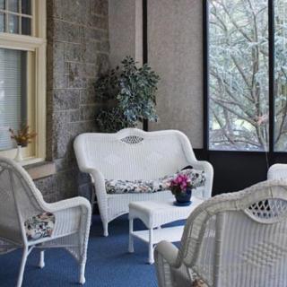 A cozy indoor patio area featuring white wicker furniture and a potted plant.