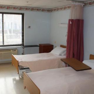 A hospital room with two beds and a separating curtain.