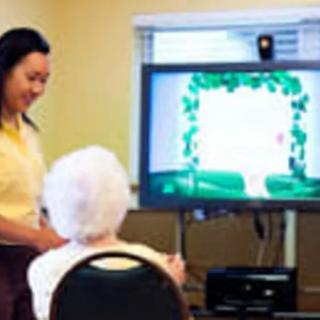 A caregiver interacting with an elderly person using a digital screen.