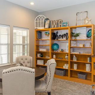 A cozy home office with a wooden bookshelf and upholstered chairs.